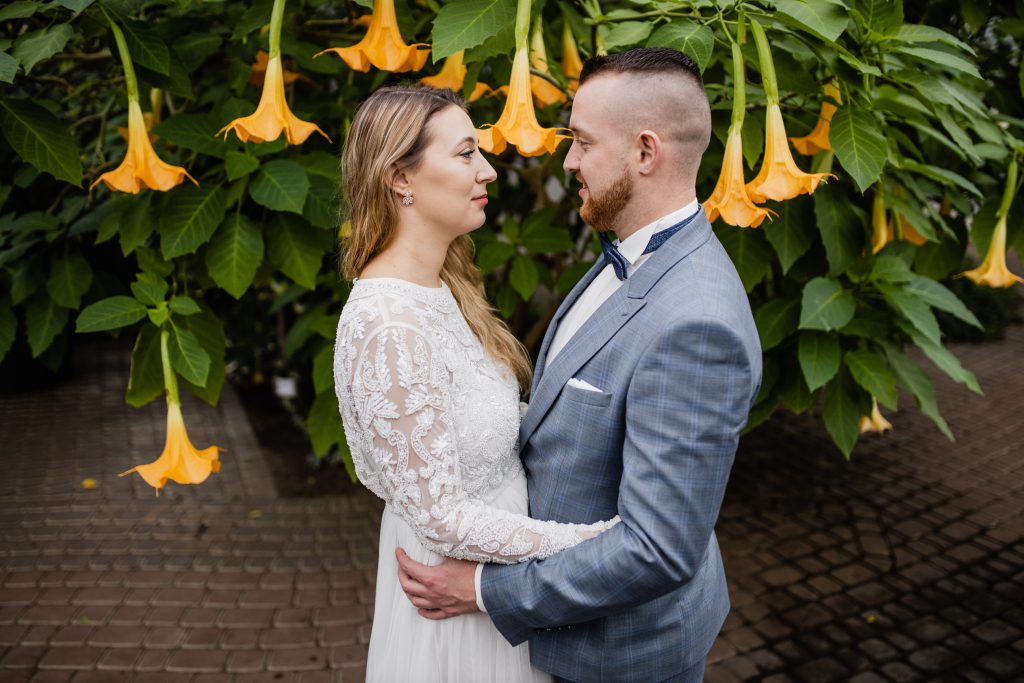a man and woman standing in front of a tree with yellow flowers